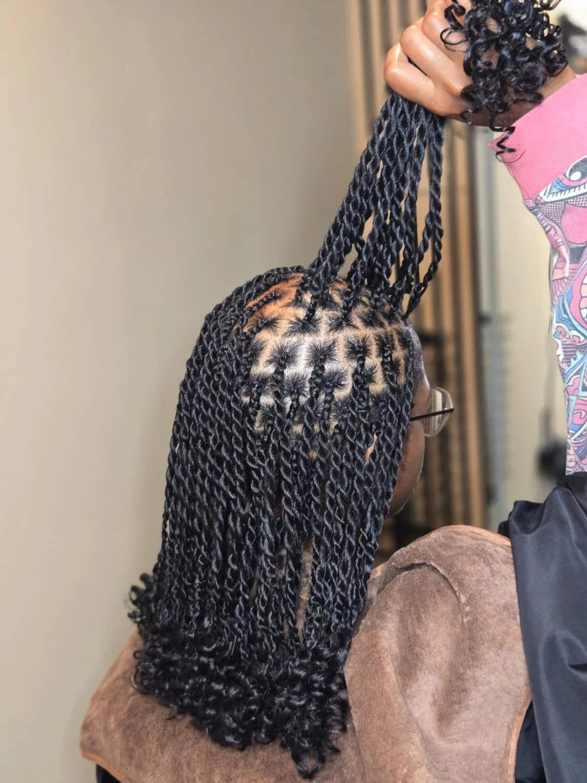 Back view of Senegalese passion twists with curly ends, being held up during styling.