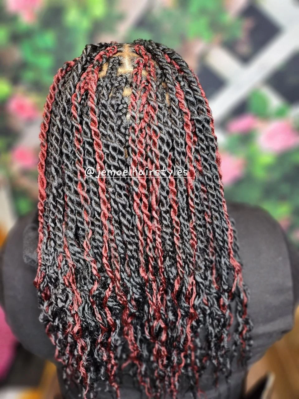 Back view of long black and burgundy twisted braids on a model.